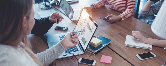 Digital Leadership Arbeitsgruppe um Notebook versammelt.
